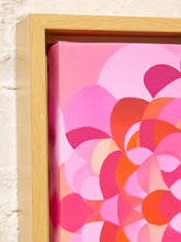 Load image into Gallery viewer, Close-up of a framed abstract floral canvas print with layered pink, magenta, orange, and peach petal-like shapes inside a light natural wood frame, set against a white textured wall.
