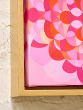 Load image into Gallery viewer, A close-up of a framed canvas print featuring a retro-style abstract floral pattern in shades of pink, coral, and orange, set in a light wood frame against a textured beige wall.
