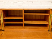 Load image into Gallery viewer, A wooden folding desk or writing table with open shelving, shown partially open against a white brick wall background.
