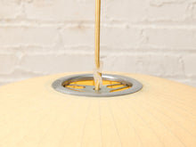 Load image into Gallery viewer, Close-up of a light beige paper lantern pendant light with a gold cord and a silver metal ring, set against a white brick wall background.
