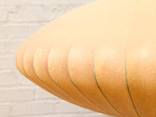 Load image into Gallery viewer, Close-up of a curved, ribbed tan leather or faux-leather surface with a light brick wall background.
