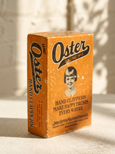 Load image into Gallery viewer, Vintage orange Oster hand clippers advertising box with illustrated portrait and John Oster Manufacturing Co. Racine Wisconsin branding
