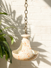 Load image into Gallery viewer, Vintage ceramic hanging bird feeder with cream glaze, orange-red speckles, open feeding area, and metal chain
