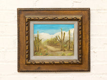 Load image into Gallery viewer, Vintage framed desert landscape painting with saguaro cacti, mountain backdrop, blue sky, and carved wood frame
