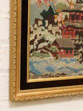 Load image into Gallery viewer, Vintage framed needlepoint artwork depicting a red pagoda, flowering tree branches, blue water, and distant mountains.

