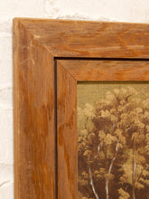 Load image into Gallery viewer, Close-up of a framed landscape painting showing a warm brown wooden frame and a detailed print of trees on a textured beige background, mounted on a white brick wall.
