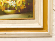 Load image into Gallery viewer, Close-up of a framed still life painting showing yellow flowers in a green bowl, with a cream and gold frame mounted on a white textured wall.
