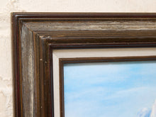 Load image into Gallery viewer, Close-up of a dark brown wooden picture frame with a textured finish, showing a cream-colored mat board and a blue sky landscape print partially visible.

