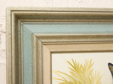 Load image into Gallery viewer, Close-up of a framed art print showing a textured light beige frame with a light blue inner frame and a cream-colored canvas featuring yellow palm leaves.
