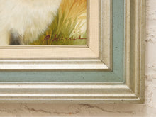 Load image into Gallery viewer, Close-up of a framed painting showing part of a white animal with yellow and green grass, featuring a distressed sage green and speckled beige frame mounted on a textured off-white wall.
