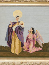 Load image into Gallery viewer, A framed needlepoint or cross-stitch artwork depicting a standing angel in a purple and gold robe next to a kneeling angel in a pink robe, set against a pale sky and dark ground, with an ornate gold frame.
