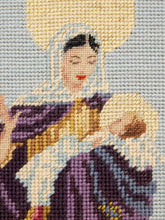 Load image into Gallery viewer, Close-up of a needlepoint canvas featuring a religious scene with a woman in a purple and gold robe holding a child, with a pale blue-gray background and a large gold halo shape at the top.
