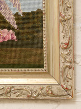 Load image into Gallery viewer, Close-up of an ornate vintage-style frame with carved scrollwork and distressed gold and red paint, showing part of a needlepoint or embroidered landscape canvas with green, brown, pink, and blue details.
