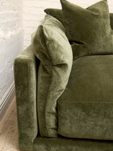 Load image into Gallery viewer, An olive green velvet sofa cushion and matching throw pillow resting on a matching green upholstered sofa, set against a white brick wall.
