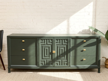 Load image into Gallery viewer, Vintage dark green credenza with six drawers, geometric carved center cabinet doors, brass-tone pulls, and slender legs
