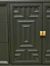 Load image into Gallery viewer, Dark olive green cabinet doors with a geometric, ribbed panel design and small gold square handles, shown in a close-up detail shot.
