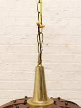 Load image into Gallery viewer, A close-up of a vintage brass ceiling fan bell and hanging chain against a white painted brick wall.
