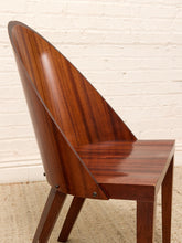 Load image into Gallery viewer, A close-up of a mid-century modern wooden chair with a glossy reddish-brown wood finish, featuring a curved backrest and angled legs, set against a white brick wall background.

