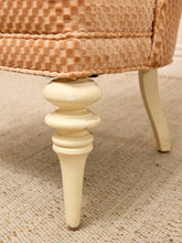 Load image into Gallery viewer, Close-up of a vintage upholstered armchair with a woven tan and beige fabric seat and turned cream-colored wooden legs on a textured beige rug.
