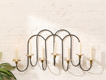 Load image into Gallery viewer, Vintage hanging wall candle holder with black metal arched frame, curved arms, and multiple aged brass candle cups

