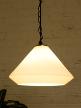 Load image into Gallery viewer, A warm white cone-shaped pendant light with a black hanging chain, shown against a textured white brick wall.
