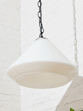 Load image into Gallery viewer, A white glass pendant light shade hanging from a black metal chain against a white brick wall.
