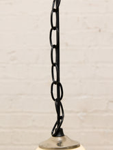 Load image into Gallery viewer, A close-up of a black metal pendant light chain with elongated oval links, attached to a silver-toned ceiling canopy against a white painted brick wall.
