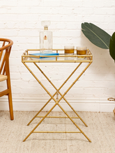 Load image into Gallery viewer, Vintage faux bamboo brass-tone tray table with rectangular clear glass top, raised gallery rail, and crossed metal legs

