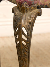 Load image into Gallery viewer, Close-up of an ornate carved wooden chair leg with a distressed brown finish and a patterned fabric seat cushion visible at the top.
