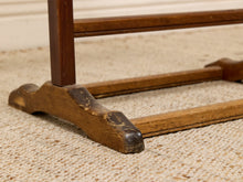 Load image into Gallery viewer, Close-up of a rustic wooden stand or rack base with carved feet, resting on a beige woven rug.
