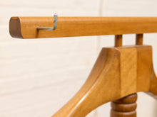Load image into Gallery viewer, Close-up of a wooden hanger bar with a silver metal hook, attached to a wooden hanger against a light off-white brick wall background.
