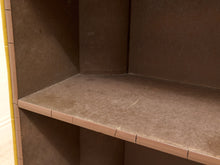 Load image into Gallery viewer, A close-up view of a wooden shelf or cabinet corner with a dusty brown surface and dark brown interior walls.
