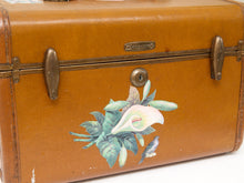 Load image into Gallery viewer, A vintage brown leather suitcase or trunk with brass latches and a painted floral design featuring a white calla lily, green leaves, and a small bird on the front.
