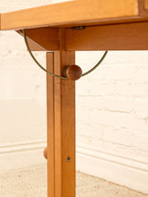 Load image into Gallery viewer, Close-up of a wooden table leg with a round wooden knob and a thin metal support rod, set against a white brick wall and light carpet.
