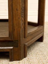 Load image into Gallery viewer, Close-up detail of a dark brown wooden table corner with visible grain, joinery, and a woven beige rug underneath.
