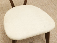 Load image into Gallery viewer, Close-up of a chair seat upholstered in textured off-white fabric, with dark brown wooden legs visible on a woven beige rug.
