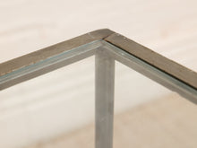 Load image into Gallery viewer, Close-up of the corner joint of a glass-top table with a distressed gray metal frame, showing the corner protector and the glass panel.
