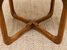 Load image into Gallery viewer, Close-up of a wooden table base with curved legs meeting in a central cross, resting on a woven beige rug.
