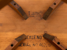 Load image into Gallery viewer, Close-up of a wooden chair underside with four dark brown wooden legs radiating from a light brown wood frame. The wood shows stamped text including 'Lane' and 'STYLE NO 598'.
