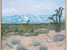Load image into Gallery viewer, A framed landscape painting depicting a desert scene with yucca plants, a Joshua tree, and snow-capped mountains under a blue sky.
