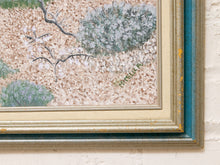 Load image into Gallery viewer, A close-up of a framed textured painting showing white blossoms on branches over a sandy beige background, with a distressed teal and gold frame mounted on a white brick wall.
