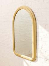 Load image into Gallery viewer, An arched wall mirror with a thick, rounded gold frame, mounted on a white painted brick wall.
