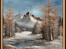 Load image into Gallery viewer, A framed landscape painting depicting a snowy winter mountain scene with bare trees, a partially frozen river, and a pale moon in the sky. The artwork is enclosed in a gold-toned frame.
