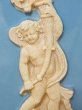 Load image into Gallery viewer, A close-up of a cream-colored classical cherub figurine holding a lyre, set against a solid light blue background.
