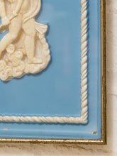 Load image into Gallery viewer, Close-up of a framed decorative wall piece with a light blue background, cream sculpted relief figure in the upper left, twisted rope border details, and a distressed gold-toned frame.
