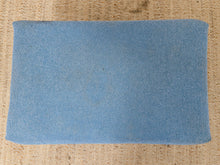 Load image into Gallery viewer, A rectangular light blue fabric pillow cover or cushion cover laid flat on a textured beige woven rug.
