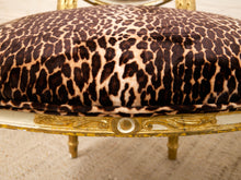 Load image into Gallery viewer, Close-up of a leopard-print upholstered cushion on an ornate gold-framed chair, with beige carpet visible underneath.
