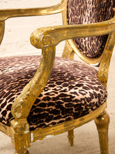 Load image into Gallery viewer, Close-up of an ornate armchair with a distressed gold frame and leopard-print upholstered seat and backrest, set against a light neutral background.
