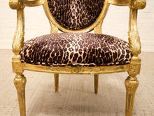 Load image into Gallery viewer, An ornate gold-framed armchair with leopard-print upholstered seat and back cushions, shown against a white brick wall and light rug.
