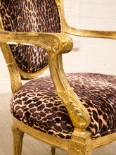 Load image into Gallery viewer, Close-up of an ornate armchair with a leopard-print upholstered seat and back, featuring carved gold-toned wooden arms and frame.
